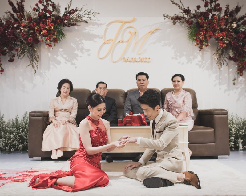Couple exchanging rings in front of their parents during the Thai engagement ceremony