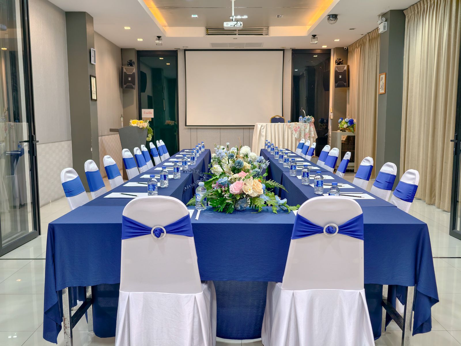 U-shape meeting set-up with blue tablecloths and floral centrepieces in Norasing 1