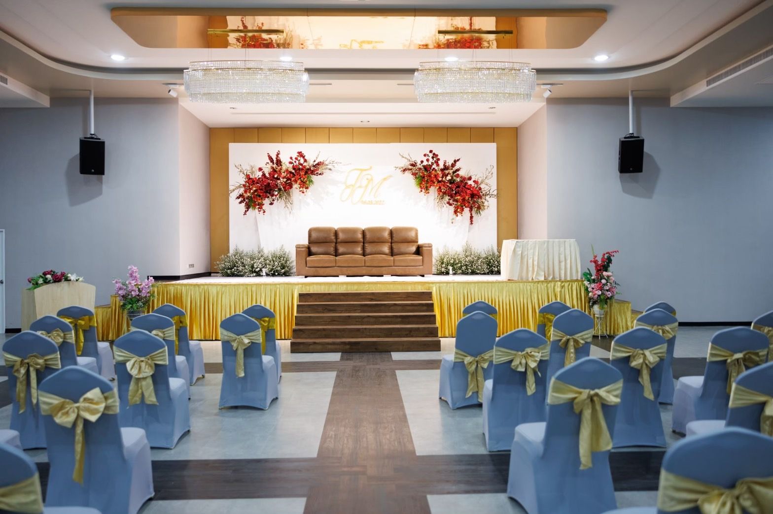 Wedding stage with a red floral backdrop and guest seating