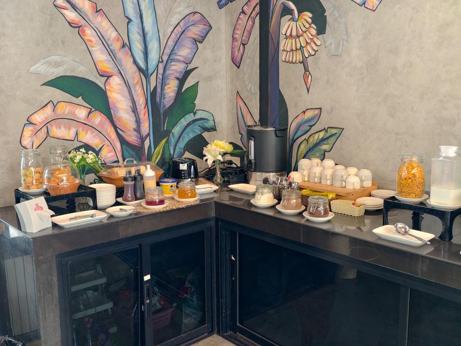 Breakfast counter with coffee and condiments beside a painted mural