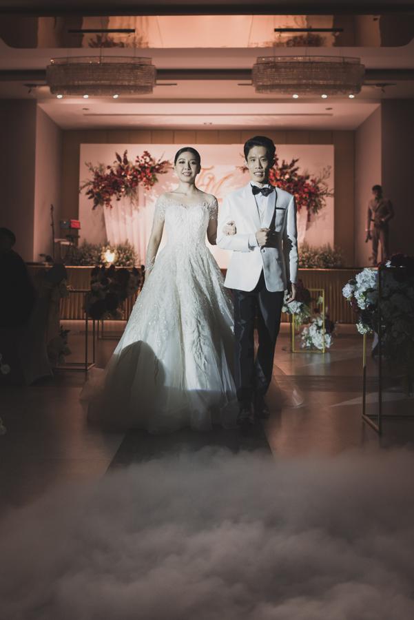 Bride and groom walking through stage fog toward their guests