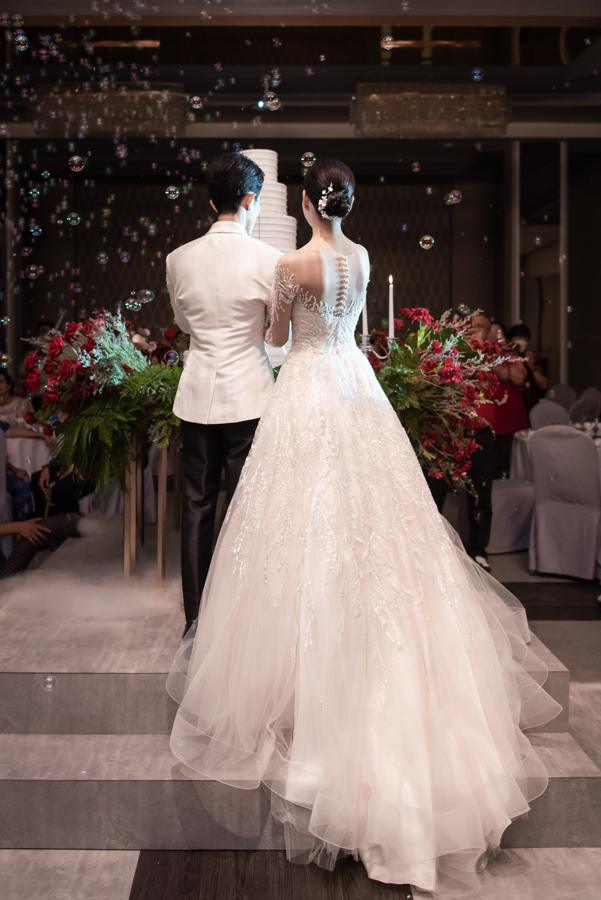 Bride and groom walking toward the wedding cake under floating bubbles