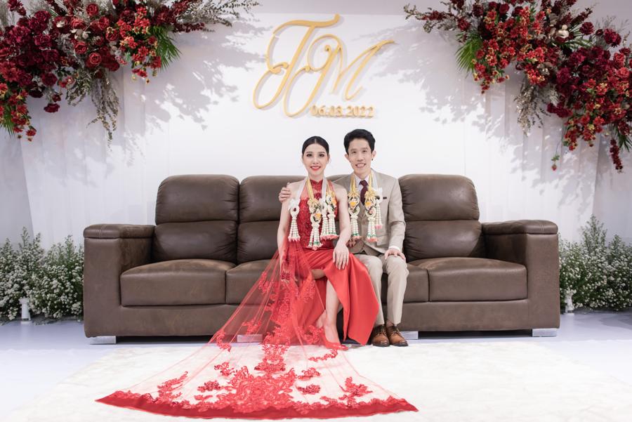 Couple wearing garlands in front of the monogram floral backdrop