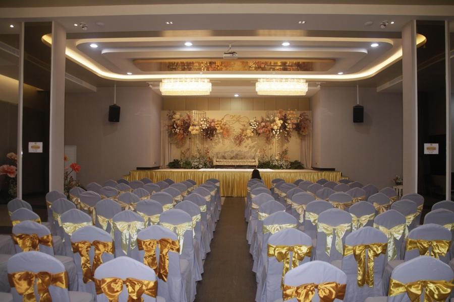 Ceremony seating with gold chair sashes beneath crystal chandeliers