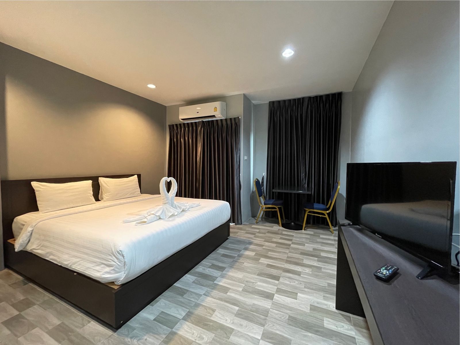 Double bed with TV and a small table by the window