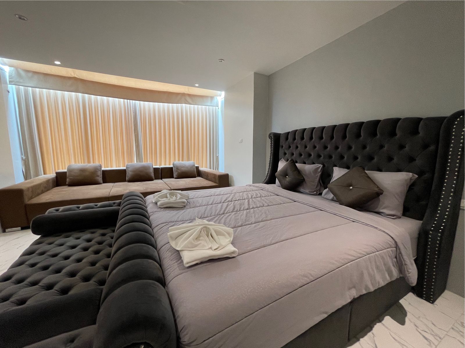 Bed with grey linen and lounge sofa