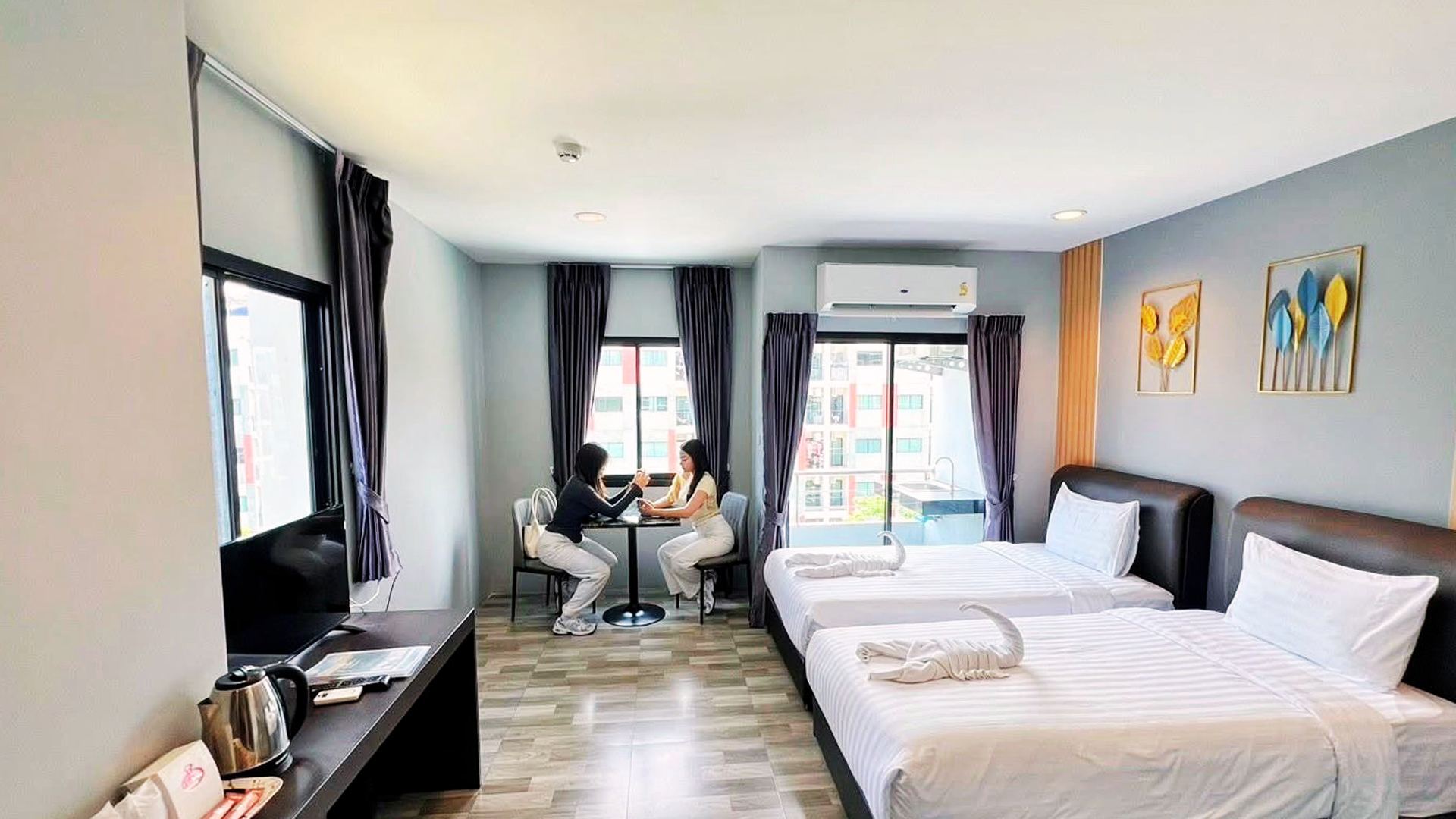 Twin room with two beds, a work desk and a small table by the window