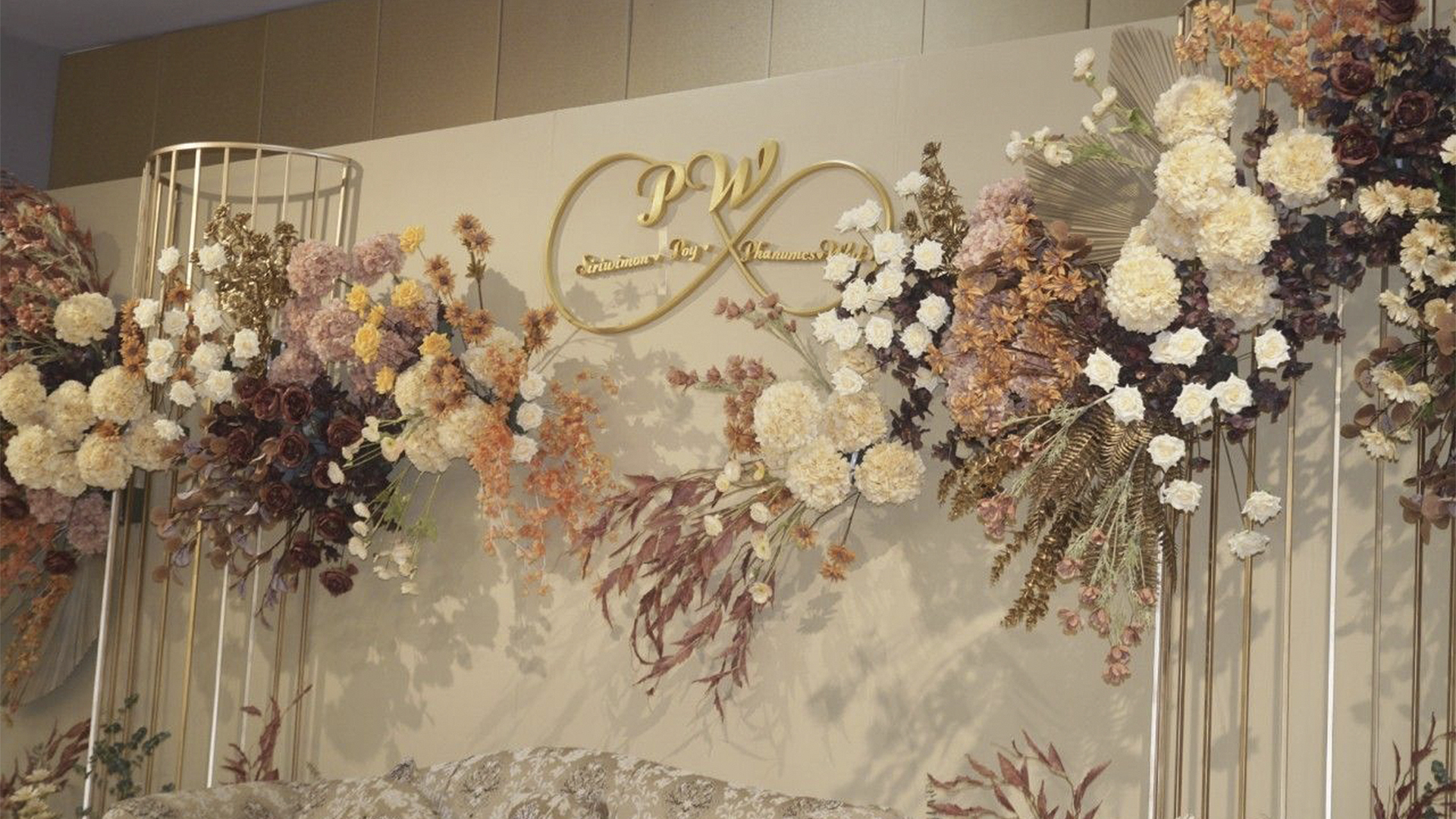 Wedding backdrop with the couple's gold monogram and autumn-toned flowers