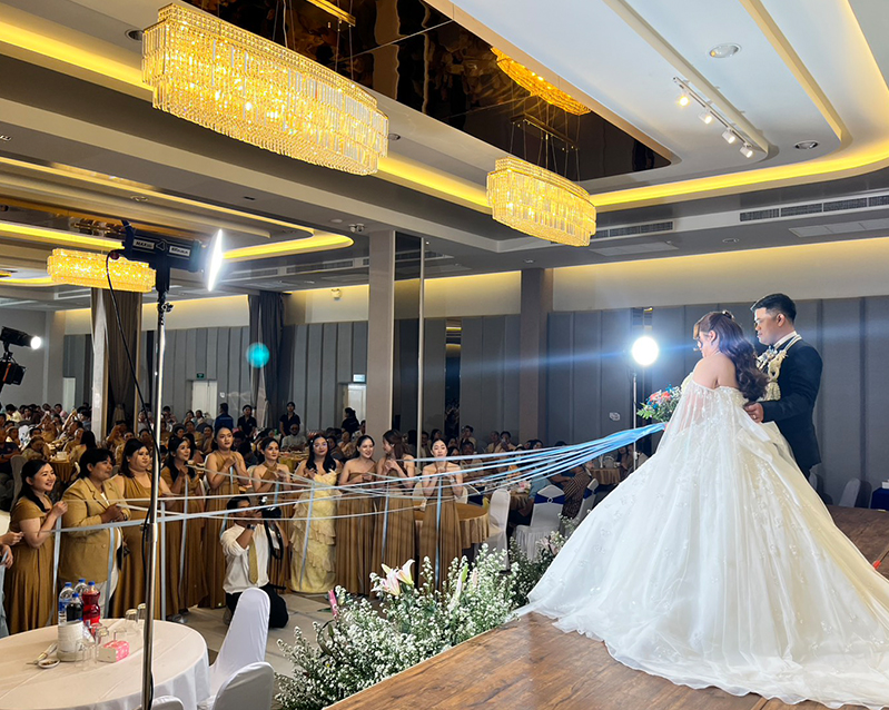 Bride and groom on stage during a ribbon ceremony with guests in the ballroom
