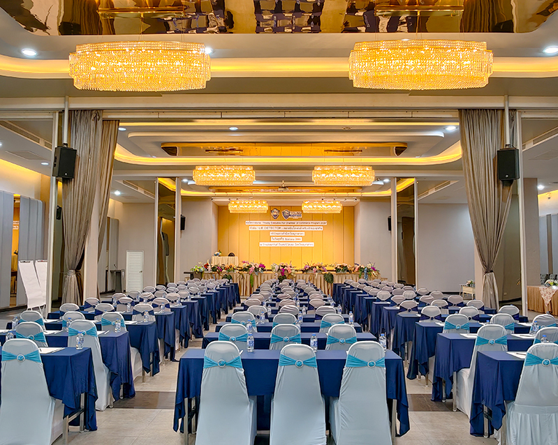 Conference setup with rows of tables facing a stage and event banner